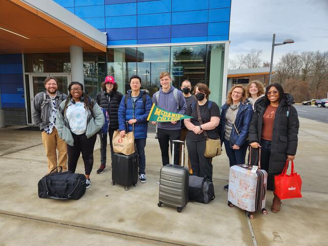 People stand with suitcases outside 