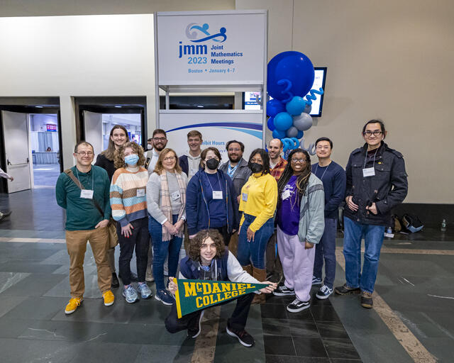 People stand in front of sign as a group 