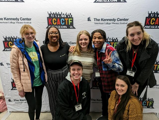 Students posing together in front of a backdrop 