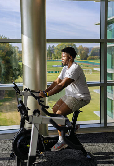A McDaniel student uses a stationary bike in front of windows in Merritt Fitness Center.