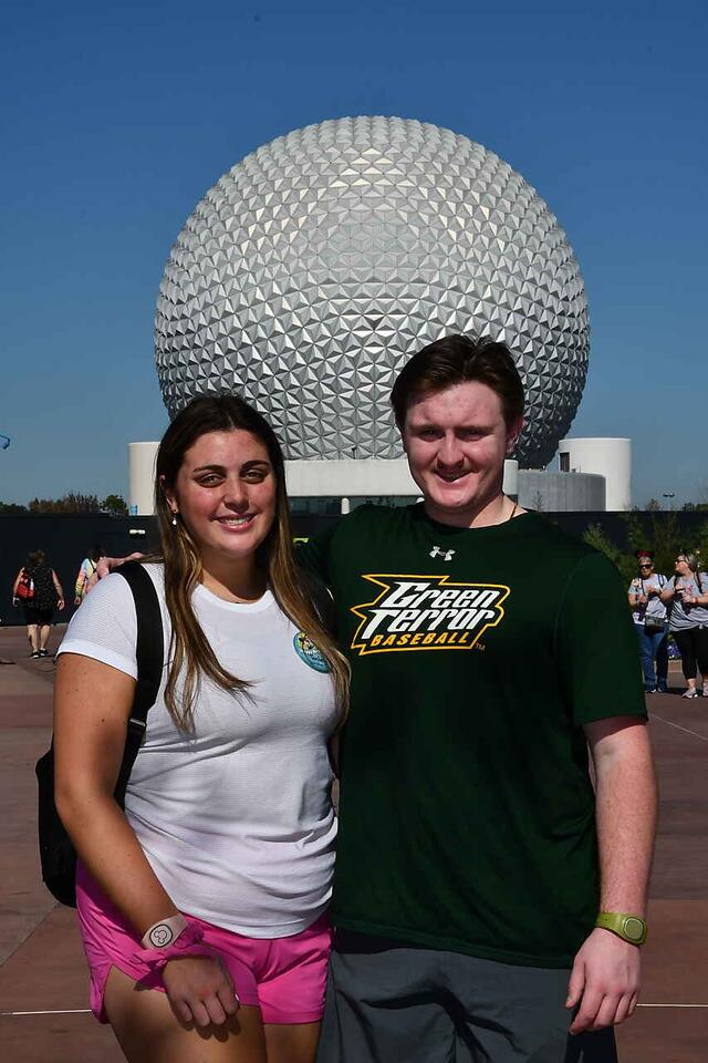 People stand in front of large white ball 