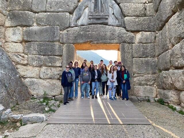 Students stand in front of architecture in Greece