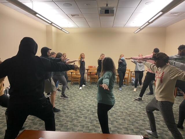 A group of people in a circle with arms extended 