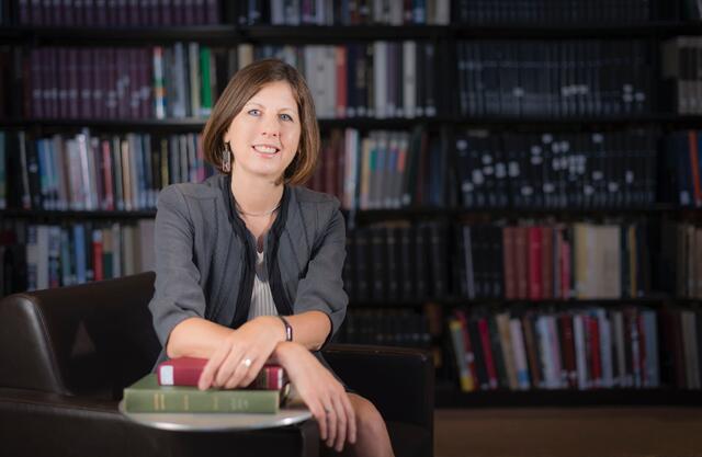 A women in front of a bookcase. 