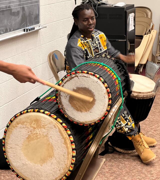 Drum instructor Paco Samb using a djembe while a student plays the dundun.