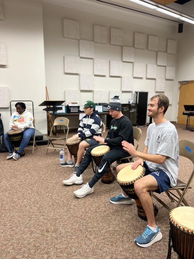 Photo of students playing drums in a classroom.
