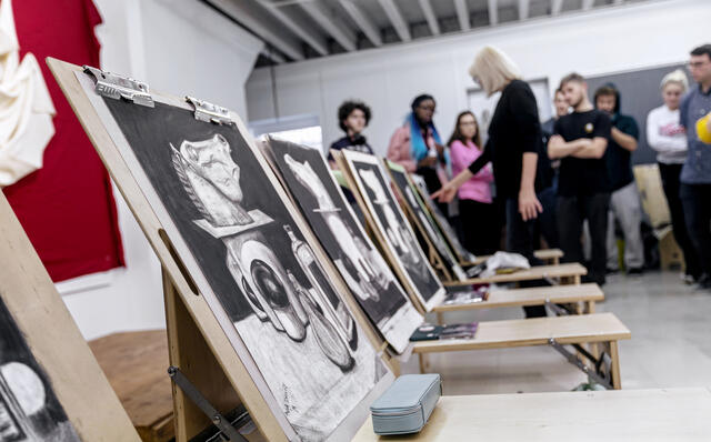 Art Professor with group of students looking over large canvas