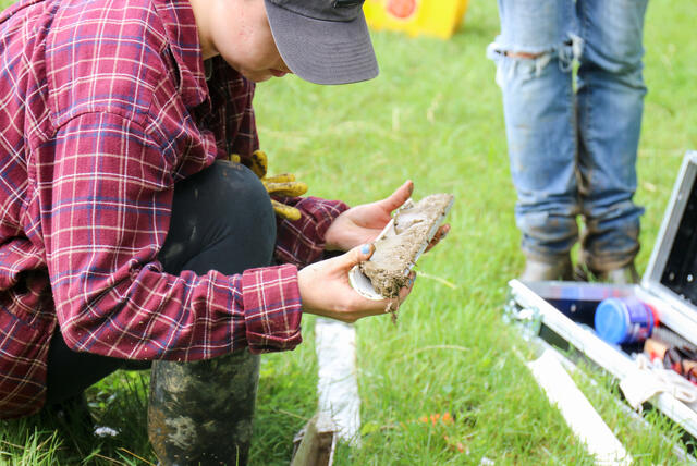 Students examine a soil sample outdoors.