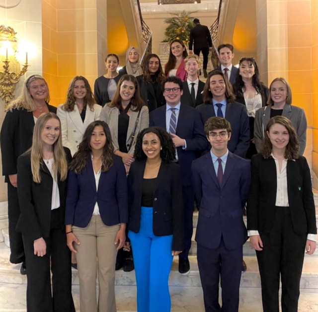 A group photo of students wearing suits and standing on a set of stairs.