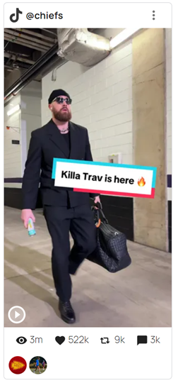 Man wearing black with sunglasses carrying a bag walking down a hallway with the text "Killa Trav is here."