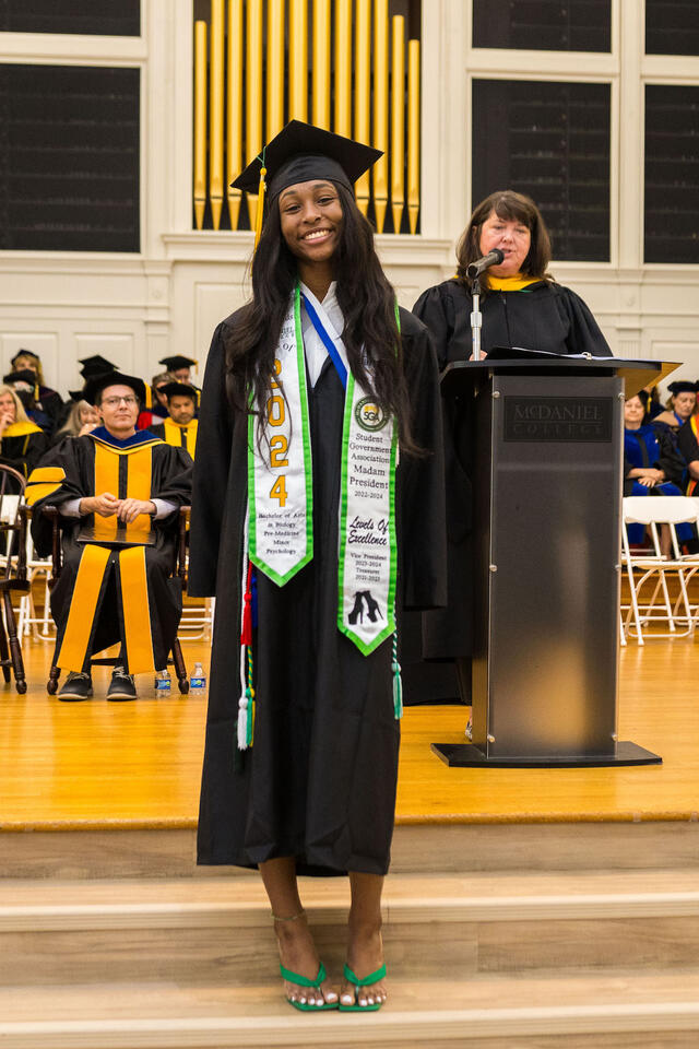 Student in graduation regalia poses