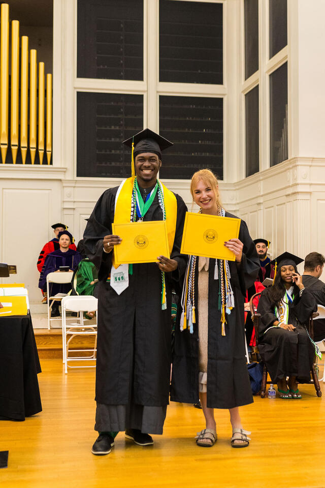 students in graduation regalia pose with awards