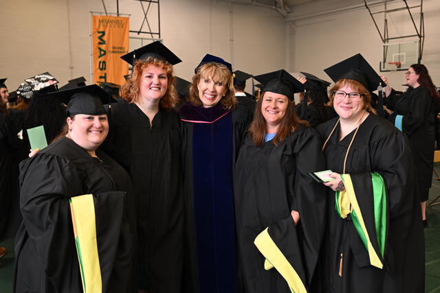 students and faculty members in regalia pose