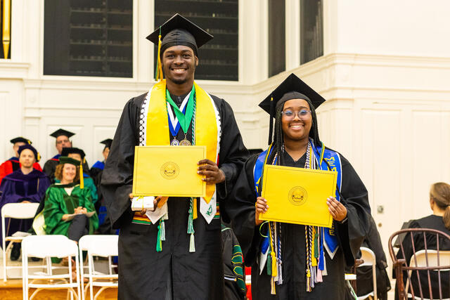 students in graduation regalia pose with awards