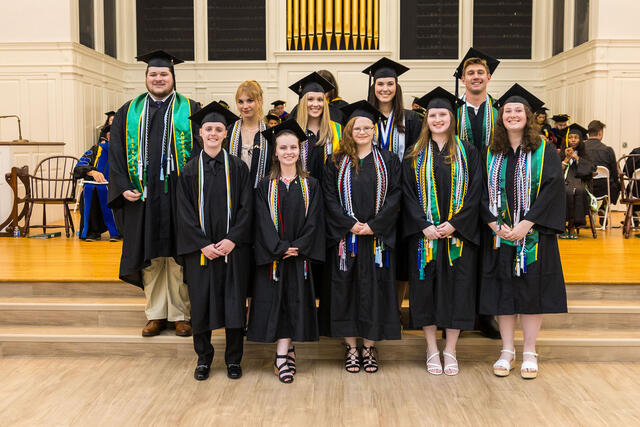 Group of students in graduation regalia pose