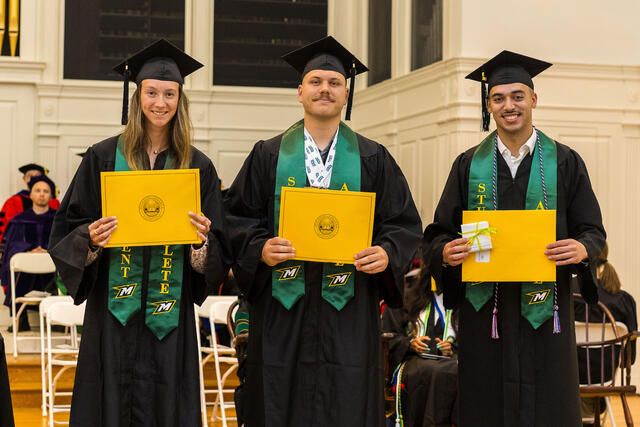 Group of students in graduation regalia pose with awards