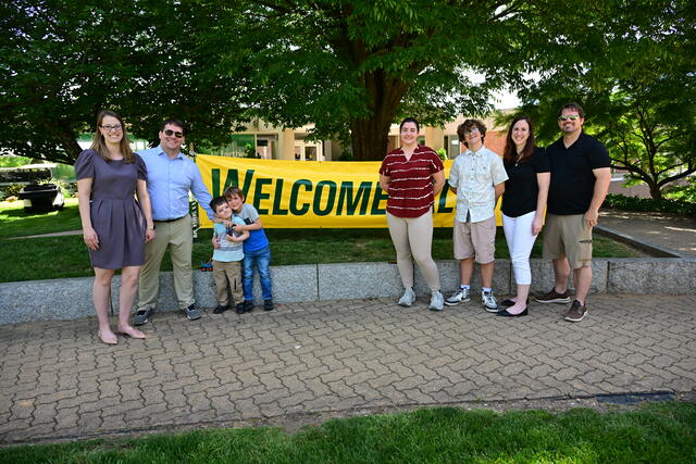Alumni Standing in Front of Welcome Alumni Sign