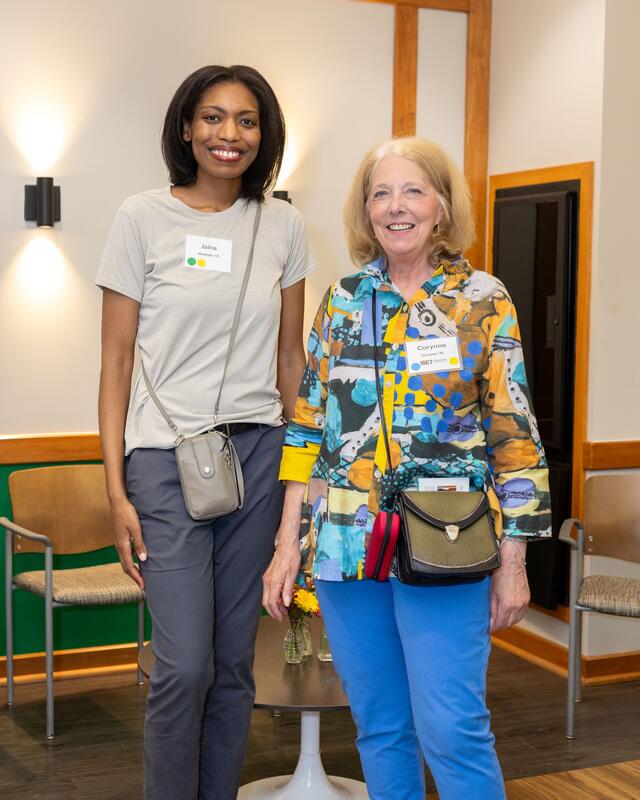 Two women stand together smiling.