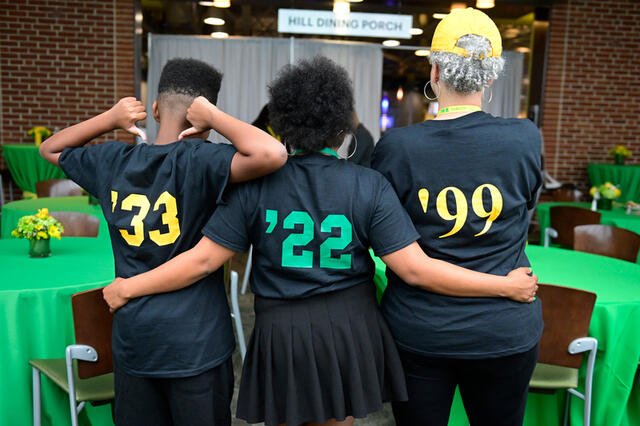 Two alums and a future alum showing off the grad years on the back of their shirts.