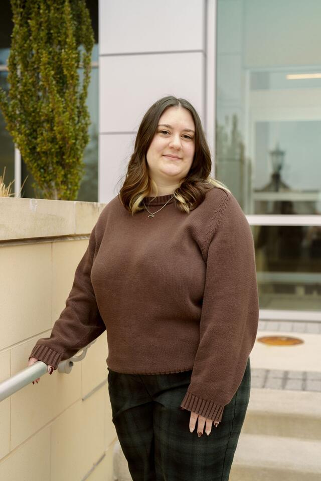 Portrait photo of Ashleigh Lobbins standing outside wearing a brown sweater.
