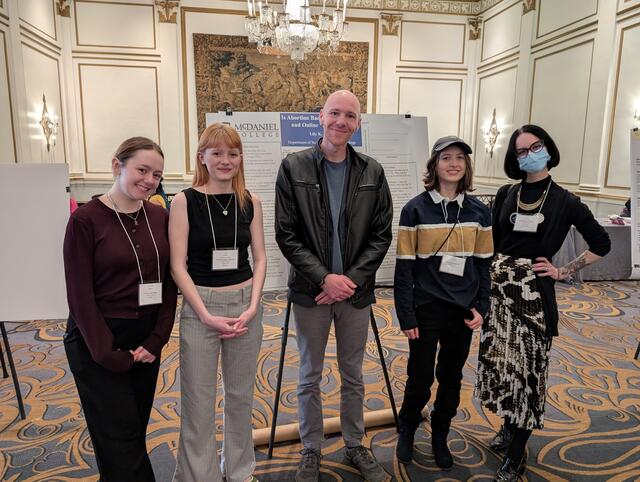 Two McDaniel Sociology professors stand with three students in front of a poster board at the 2025 Eastern Sociological Society Conference in Boston
