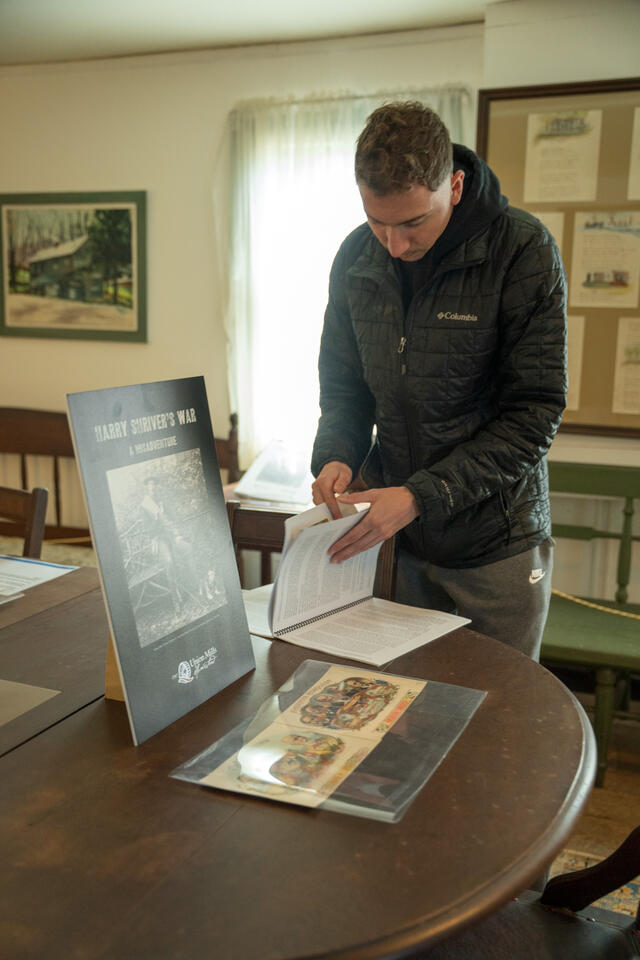 A McDaniel student flips through a book on a dining room table in Union Mills Homestead.