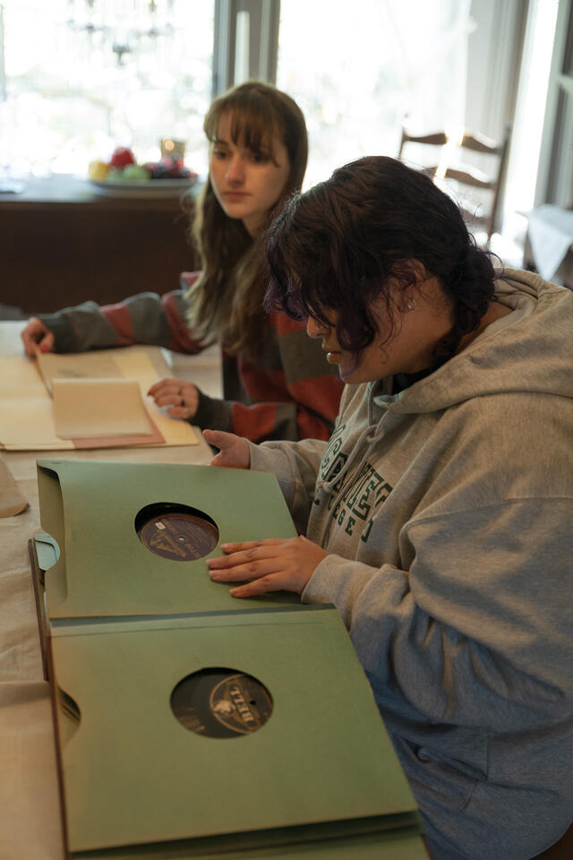 Two students sit at a table and look at archive materials.
