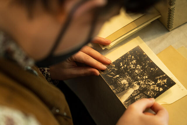 Close up image of a student holding a historical, black and white photo in their hands. In it, a figure wears a historical dress.