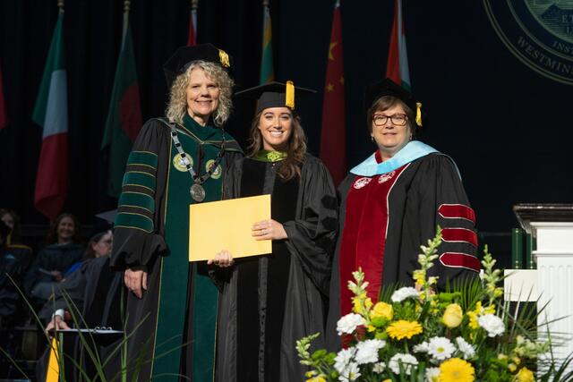 Shelton Award winner Jamie Rooney stands beside President Julia Jasken and Dean of Graduate and Professional Vickie Mazer on stage at Commencement. and