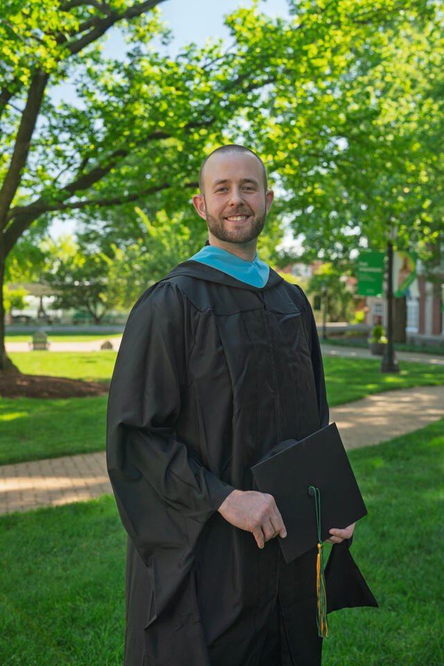 Alexandre Dubsky poses outdoors while wearing his graduation robe.