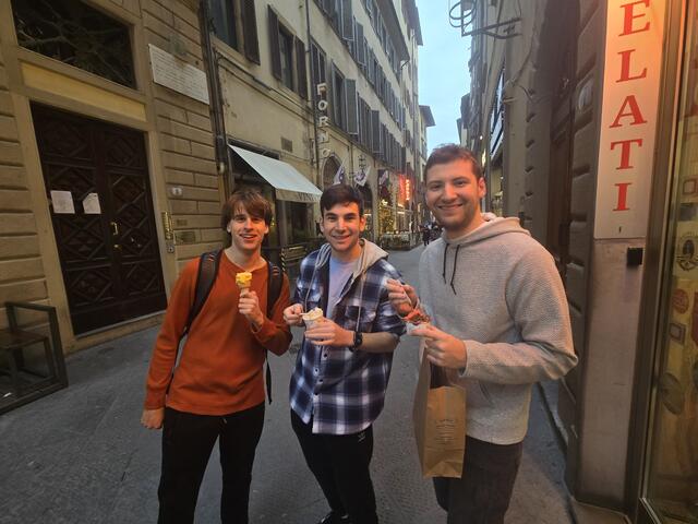 Three students holding gelati while standing outside on an Italian street.