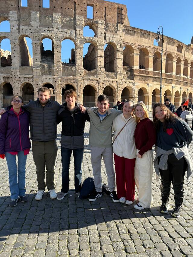 A group of students pose together in front of the Colosseum.