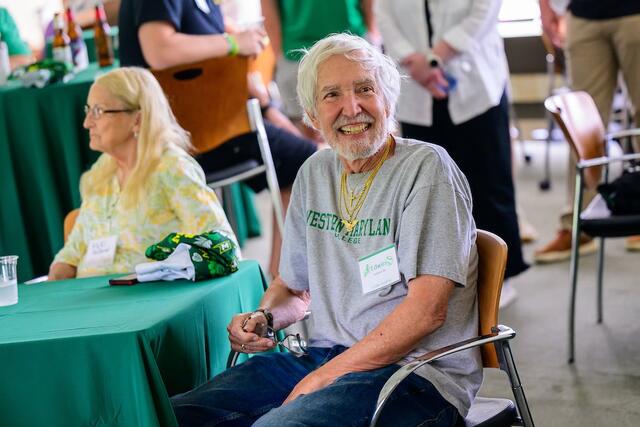 An alum smiling big at the Green & Gold happy hour.