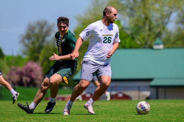 An alum boots the ball downfield at the Men's Soccer alumni game.