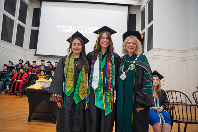 Students in graduation regalia pose with President Julia Jasken, also in graduation regalia