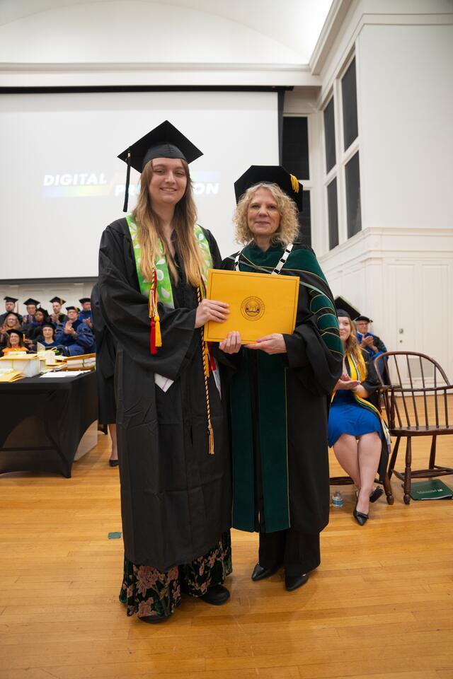 Student in graduation regalia poses with President Julia Jasken, also in graduation regalia