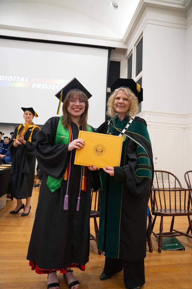 Student in graduation regalia poses with President Julia Jasken, also in graduation regalia