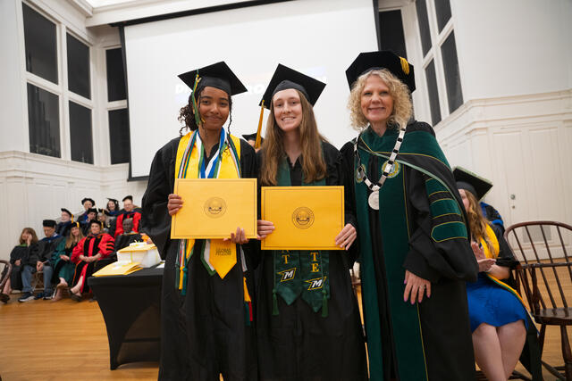 Students in graduation regalia pose with President Julia Jasken, also in graduation regalia