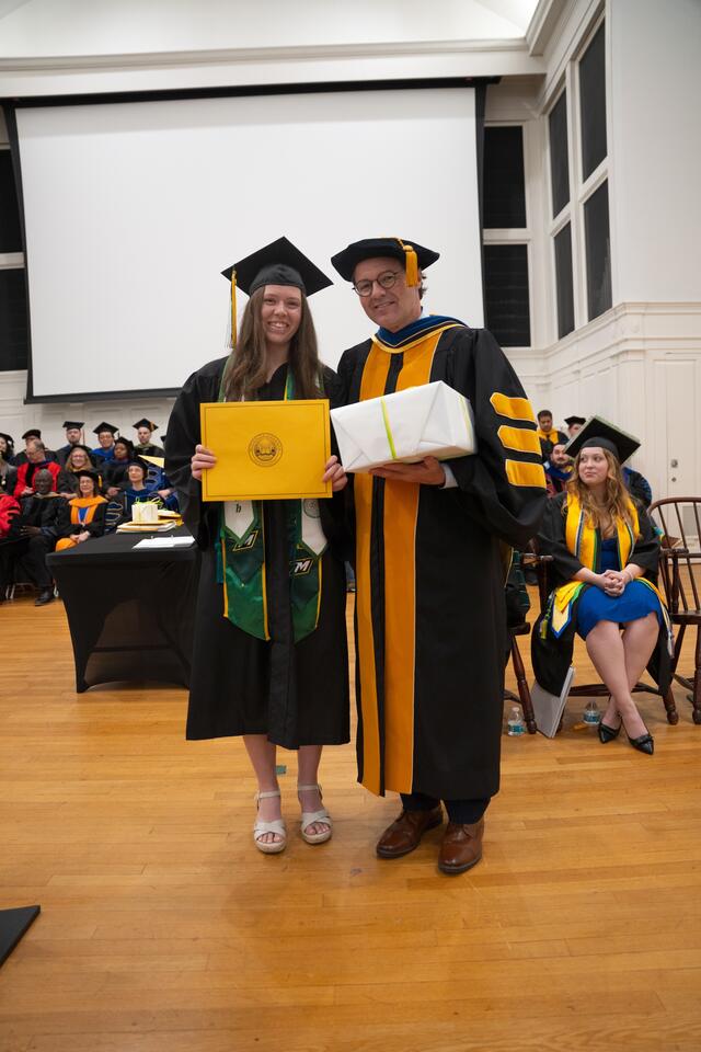 Student in graduation regalia poses with Provost Flavius Lilly, also in graduation regalia