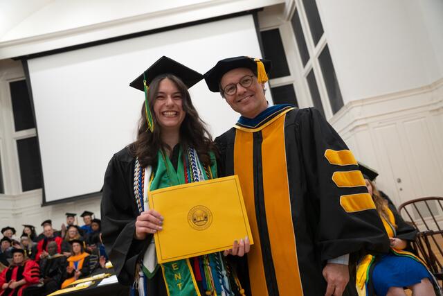 Student in graduation regalia poses with Provost Flavius Lilly, also in graduation regalia