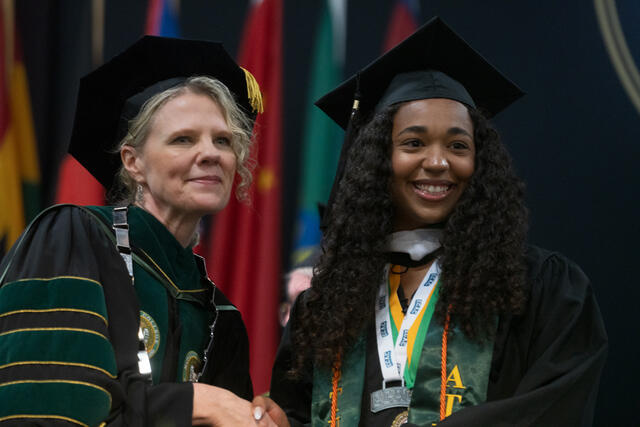 McDaniel's president hands a diploma scroll to a graduate 