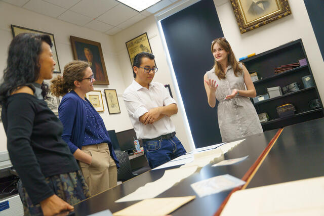 A group of people discuss historical letters in the McDaniel archives.