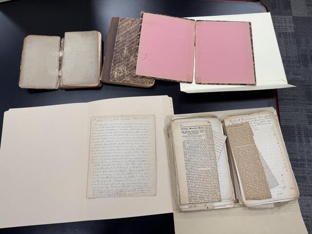Historic diaries, letters, and newspaper clippings from the 19th century spread on a table.