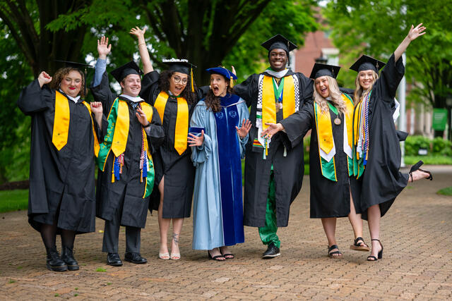 A group of graduates cheer in their regalia.
