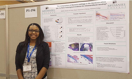 Adelle Laniyan in front of her poster. 