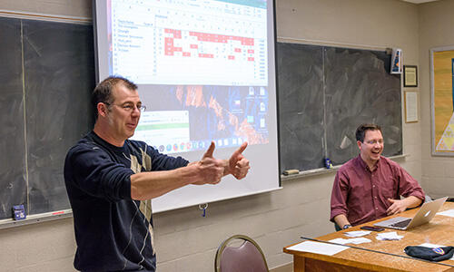 Math professor Spencer Hamblen gives two thumbs up to PChem, the winning Estimathon team, while Physics professor Jeff Marx cheers from the judge's desk.