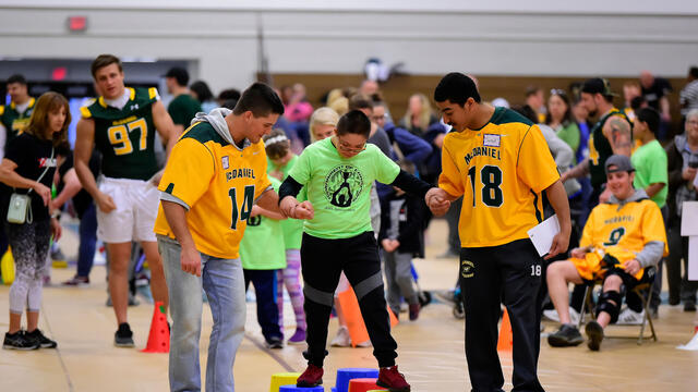 McDaniel students Michael Scott, left, and senior Jared Payne, both lacrosse players, cheer on Tournament of Champions athlete Jason Rivas, a seventh-grader at Montgomery Village Middle School.