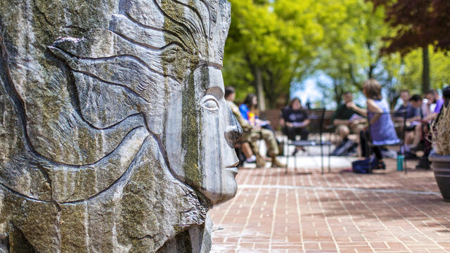 Sculpture outside of Hoover Library with students in background.