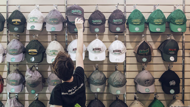 Student selecting McDaniel hat in campus bookstore.