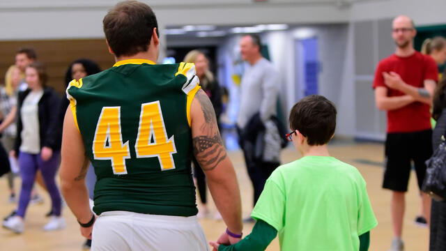 Football player holding child's hand at Tournament of Champions